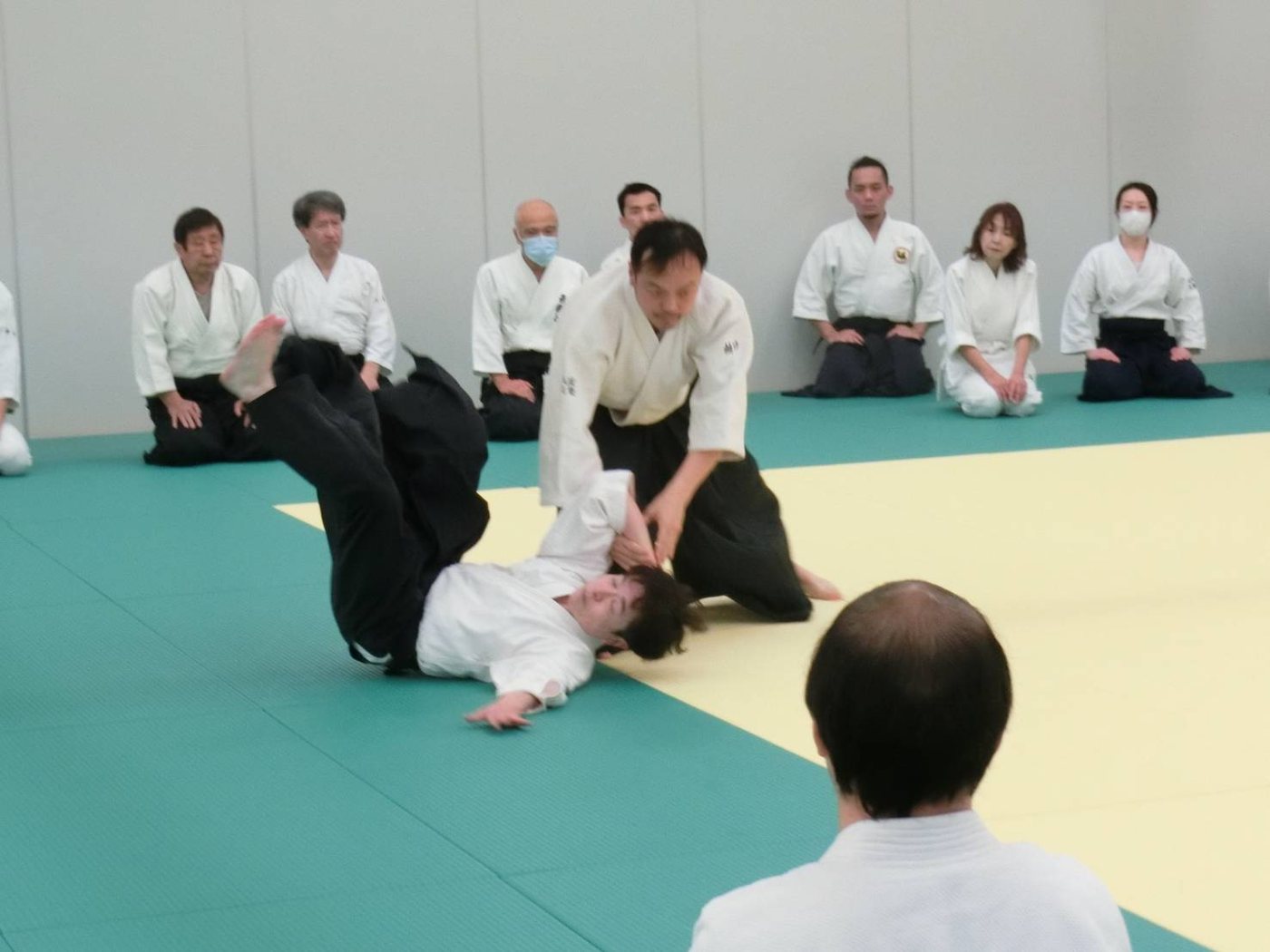 技が決まった瞬間。周囲の参加者が正座して見ている
